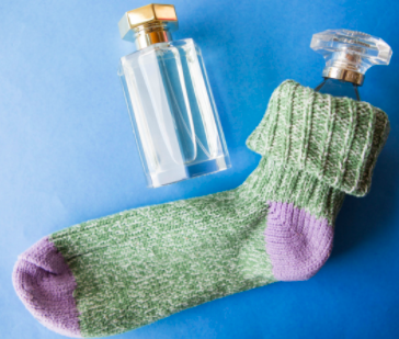 一只玻璃香水瓶塞在一只棉袜里. 另一瓶香水瓶放在这对香水的旁边.